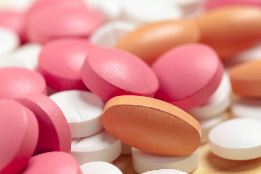 Assorted pharmaceutical medicine pills, tablets on wooden background разноцветные таблетки