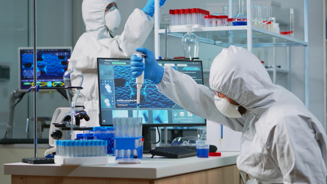 Scientist in protection suit using micropipette filling test tubes исследовательский центр