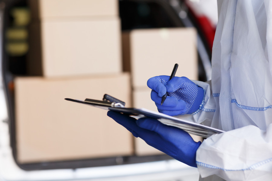 Close up of man in protective suit checking delivery in list