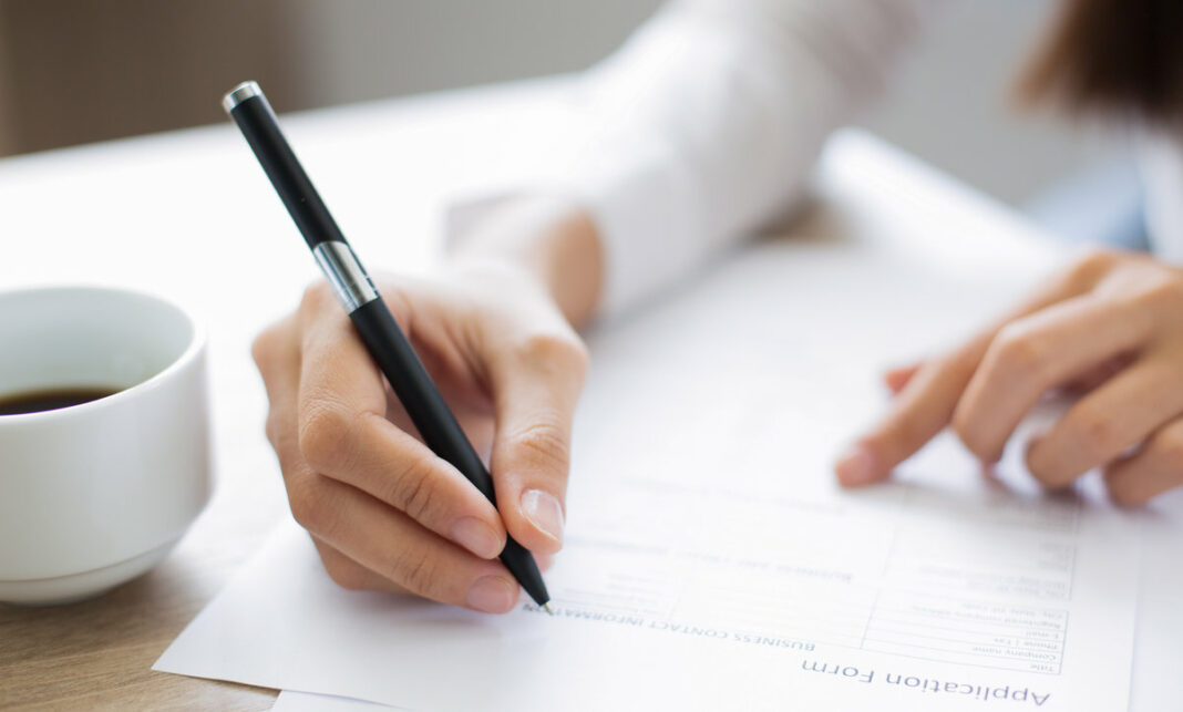 Closeup of Applicant Completing Application Form оценочный лист