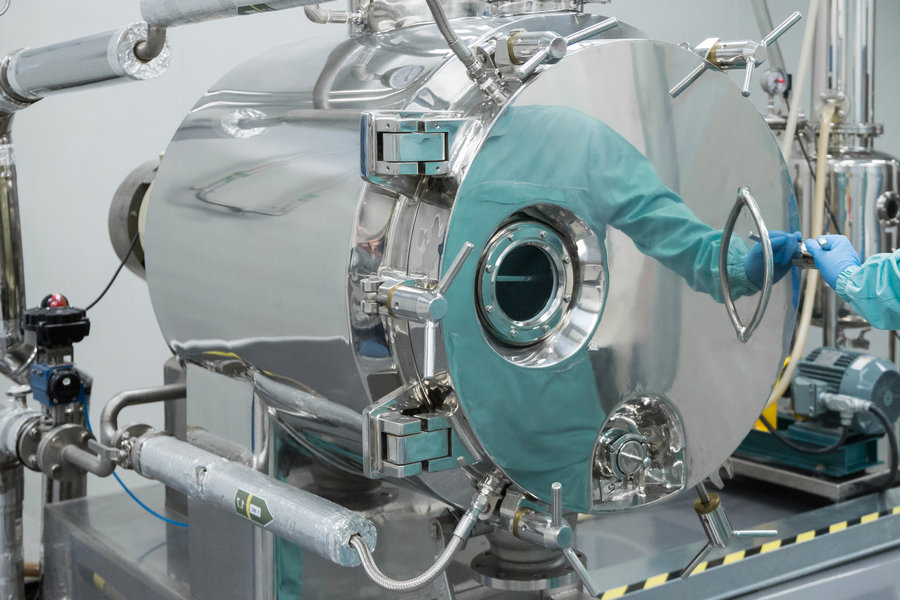 Pharmaceutical factory man worker in protective clothing working on equipment in sterile working conditions Фармацевтическое произвводство