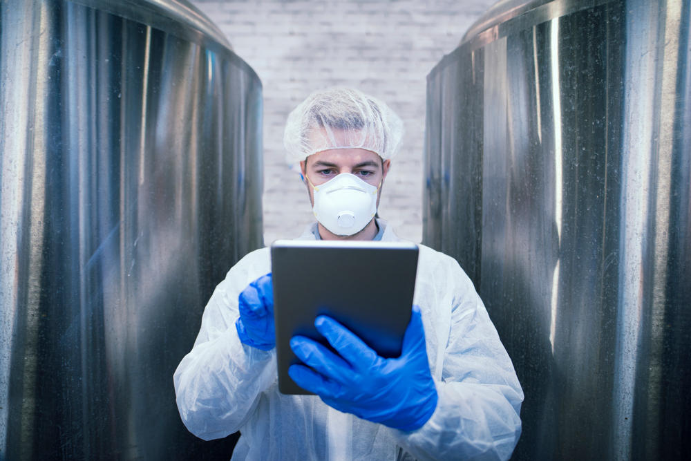 Portrait of technologist in white protective uniform holding tablet in food production factory. Клуб качества в Узбекистане
