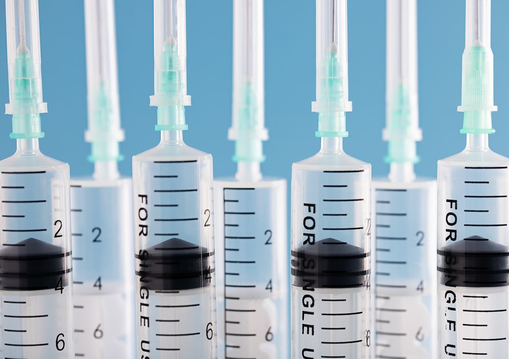 Closeup of rows of syringes over a blue background. Vaccine, COVID-19, coronavirus concept шприцы