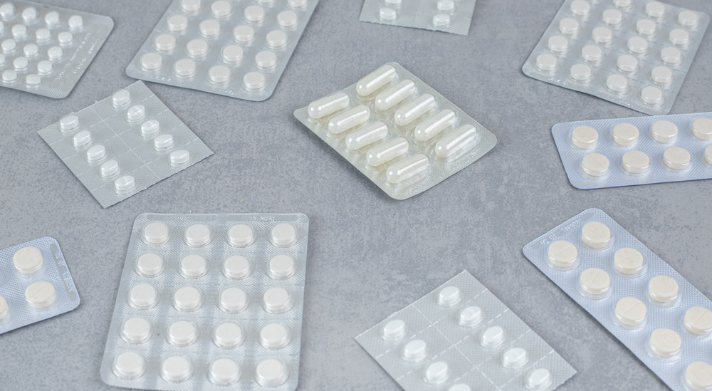 A lot of blisters with white pills on gray background таблетки в блистерах