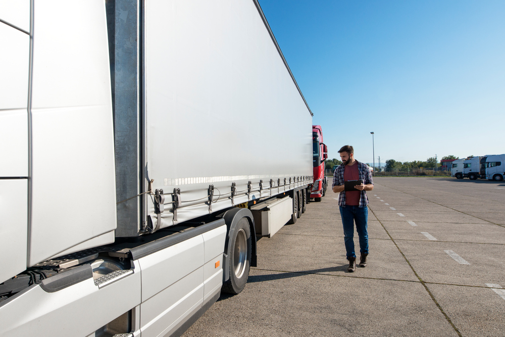 Truck driver inspecting vehicle, trailer and tires before driving. Грузовые перевозки